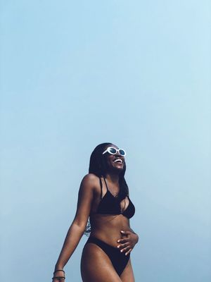 Low angle view of woman wearing bikini while standing against blue sky