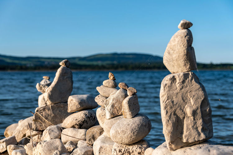 Stack of rocks by sea against clear sky