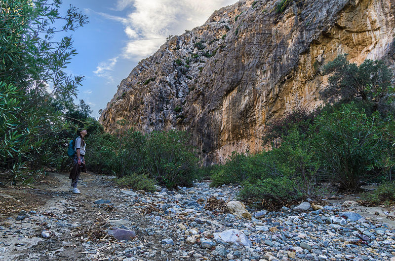 Man climbing on rock against sky