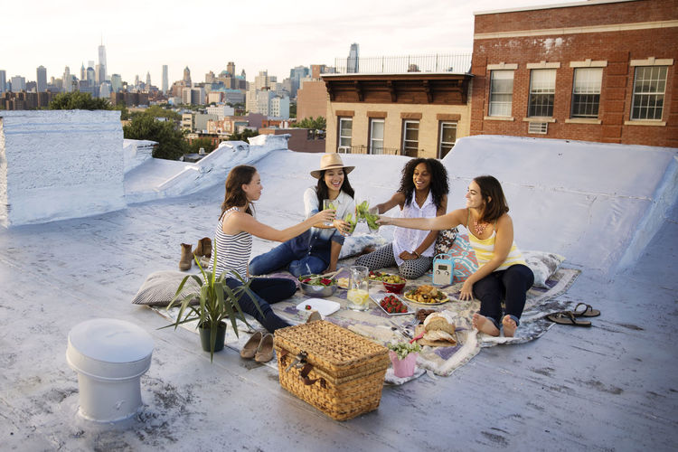 Friends toasting drink while enjoying at party on building terrace