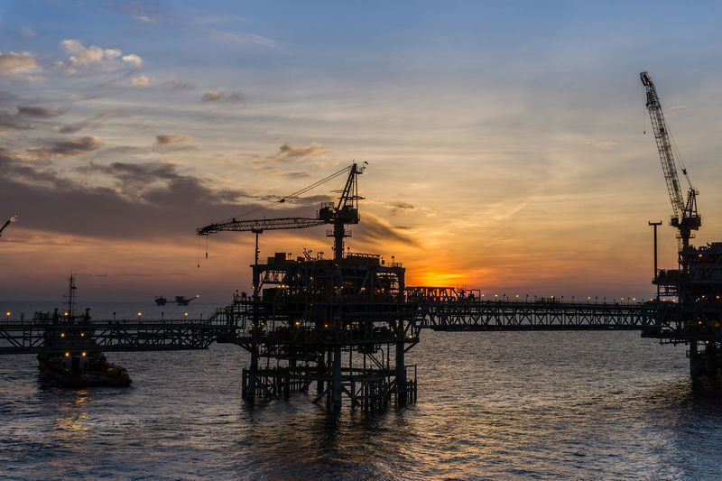 Silhouette of oil platform during sunset at offshore oil field