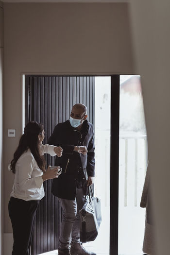 Male and female colleagues doing elbow bump while maintaining social distancing at home