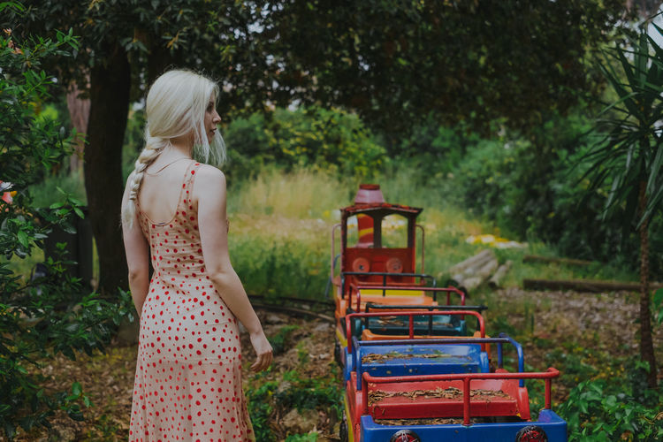 Rear view of young woman standing by miniature train at park