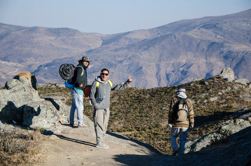 People standing on rocks against mountain range