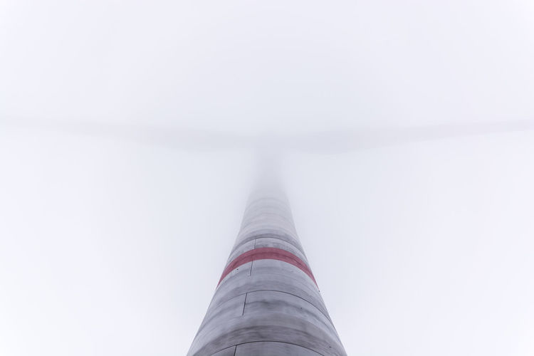 Low angle view of wind turbine in foggy weather