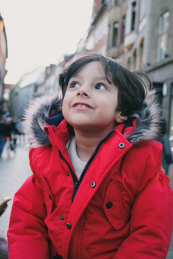 Portrait of cute 4 year old boy wearing red jacket looking away 