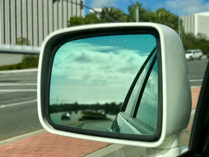 Close-up of side-view mirror with reflection