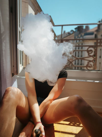 Woman exhaling smoke while sitting in balcony