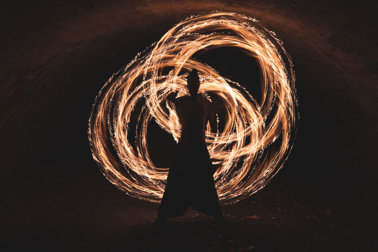 Young man performing fire ring skill in dark tunnel