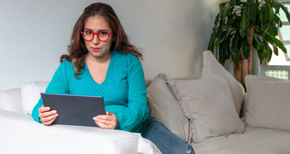 Young woman using phone while sitting on sofa at home