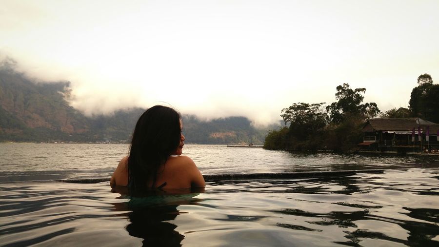 Rear view of naked woman swimming in lake