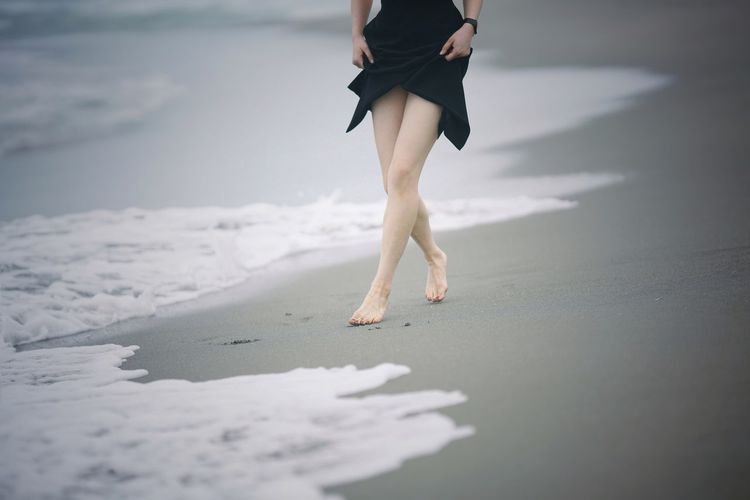 Low section of woman walking on beach