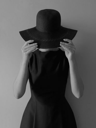 Midsection of woman wearing hat against wall