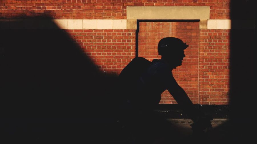 Silhouette man standing against brick wall