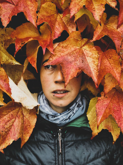 Close-up portrait of young woman with autumn leaves