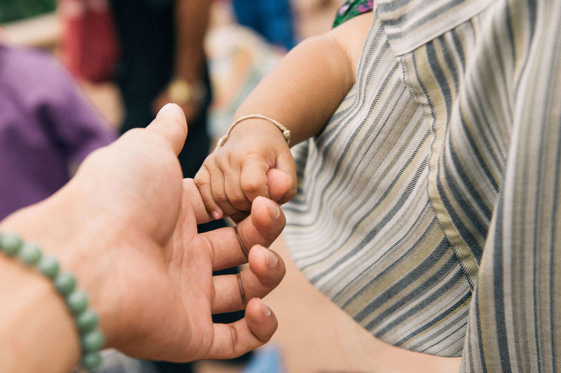 Cropped image of child holding woman hand