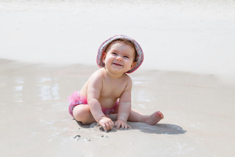 Adorable little girl is playing with sand at beach near to sea. sensory development for kids. 