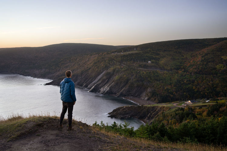 Rear view of man looking at mountains against sky