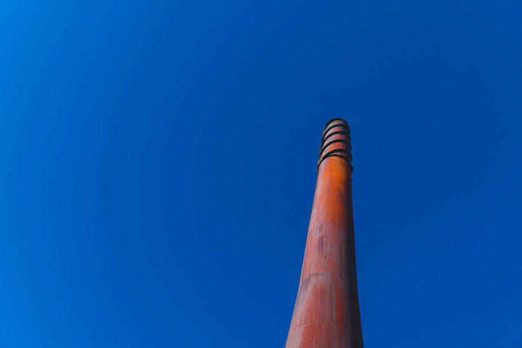 Low angle view of smoke stack against blue sky