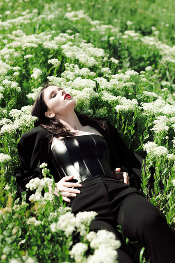 Girl model in black outfit laying on white flowers in field