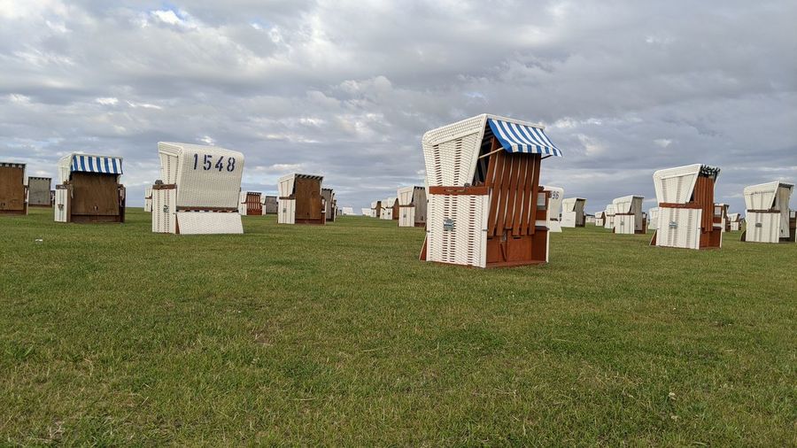 Hooded beach chairs on field against sky