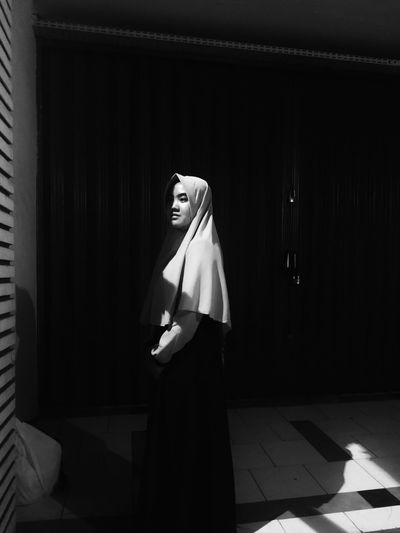 Portrait of woman in hijab looking standing in darkroom