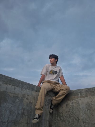 Portrait of man standing on rock against sky