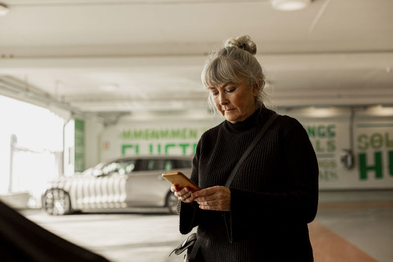 Senior woman with cell phone in parking lot