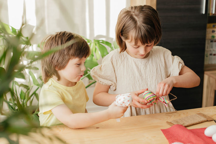A boy and a girl, sibling are crafting easter eggs from cloth in the shape of a bunny. family 