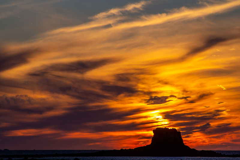 Scenic view of sea against dramatic sky during sunset