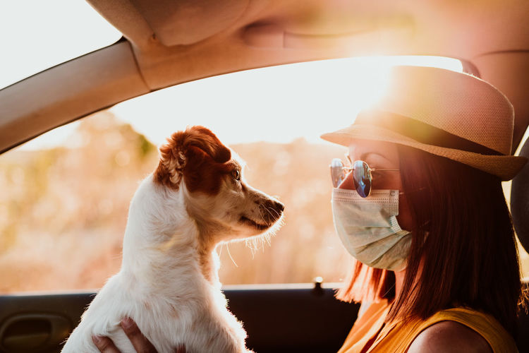 Close-up of woman wearing mask holding puppy in car