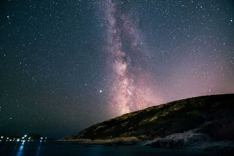 Scenic view of sea against star field at night with milky way and planet jupiter 