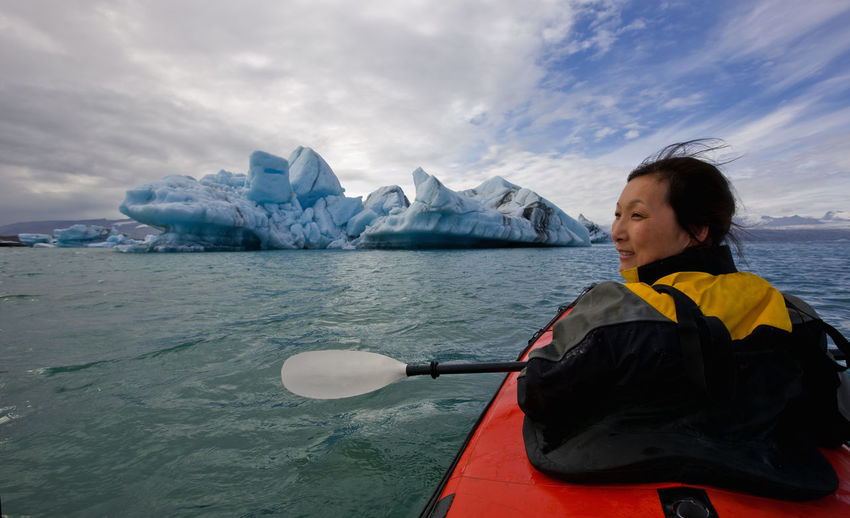 Woman rowing sea kayak on jökulsárlón glacier lagoon in iceland
