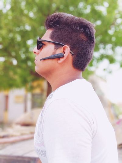 Side view of young man wearing hands-free device
