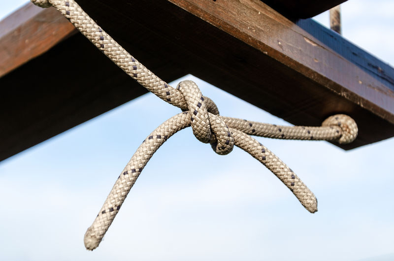 Low angle view of rope tied to wooden post