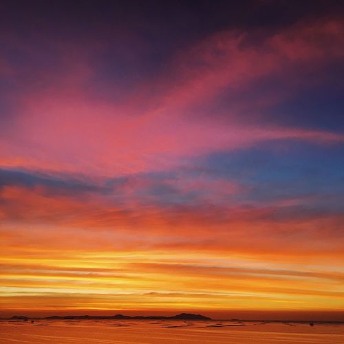 Scenic view of sea against dramatic sky during sunset