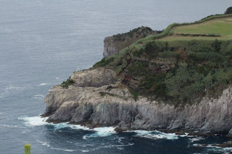 Scenic view of sea by cliff against sky