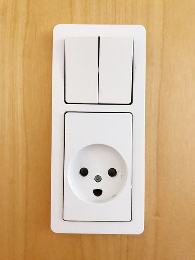 Close-up of light switch on wooden wall