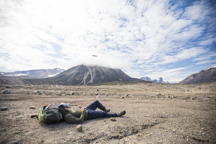 Man lying down on land against sky