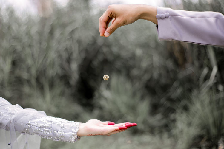 Cropped image of man throwing wedding ring on bride hand