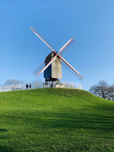 Traditional windmill on field against clear sky