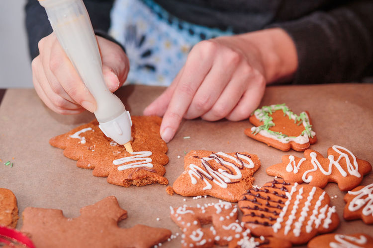 Cropped hand of woman preparing gingerbread cookies on table