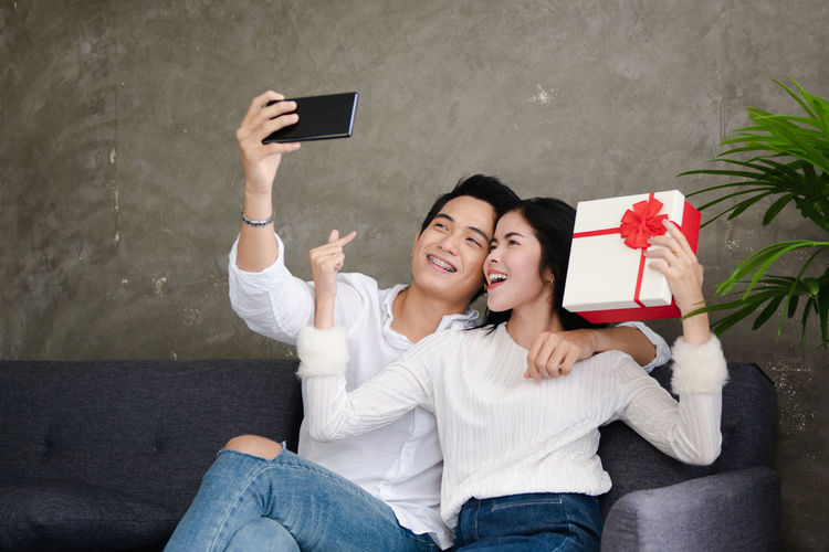 Young couple photographing with mobile phone outdoors