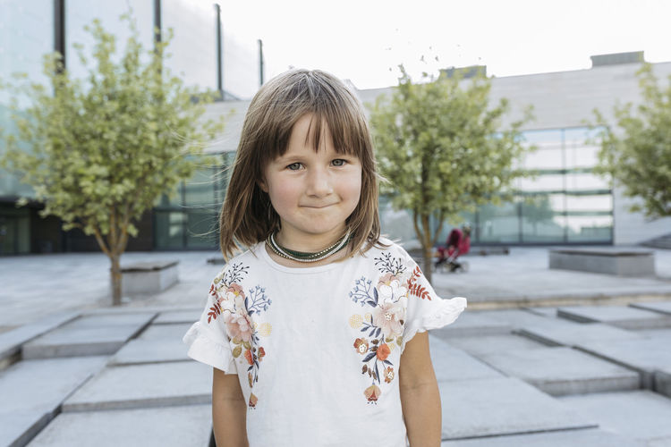 Portrait of a little girl outside in summer at glass building