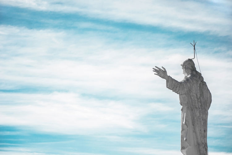 Low angle view of jesus christ statue against cloudy sky