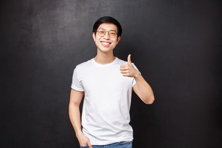 Man showing thumbs up against black background