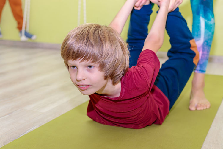 A woman instructor in a sports uniform is engaged in yoga with a boy. 