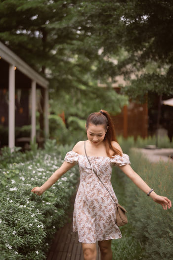 Young woman with arms outstretched standing against plants