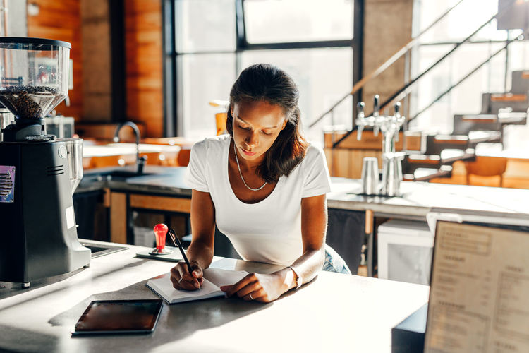WOMAN USING MOBILE PHONE WHILE STANDING IN OFFICE