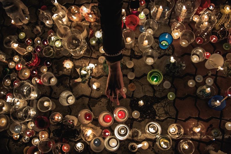Cropped hand arranging candles on cobble street at night